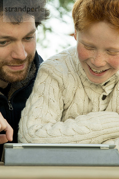 Vater und Sohn benutzen gemeinsam ein digitales Tablett