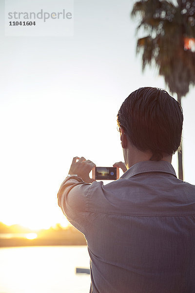 Mann fotografiert Sonnenuntergang mit Smartphone
