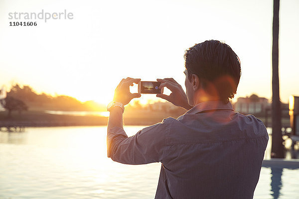 Mann fotografiert Sonnenuntergang mit Smartphone