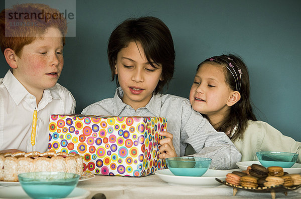 Kinder beim Anblick eines verpackten Geschenks auf der Geburtstagsfeier