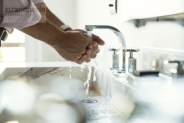 Mann beim Händewaschen im Waschbecken  abgeschnitten