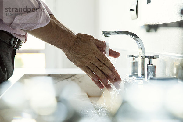 Mann beim Händewaschen im Waschbecken  abgeschnitten