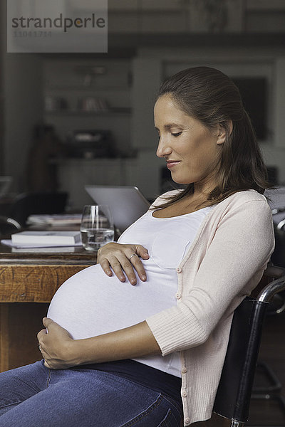 Schwangere Frau wiegt Bauch  Porträt