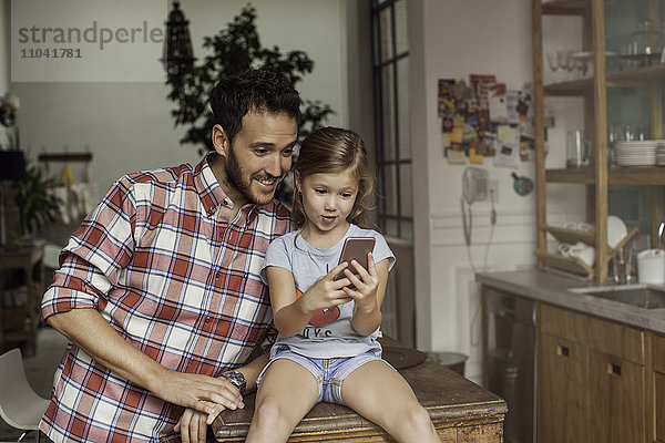 Vater und Tochter schauen gemeinsam auf das Smartphone