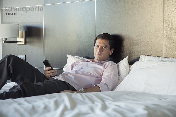 Mann entspannt sich nach der Arbeit beim Fernsehen im Bett