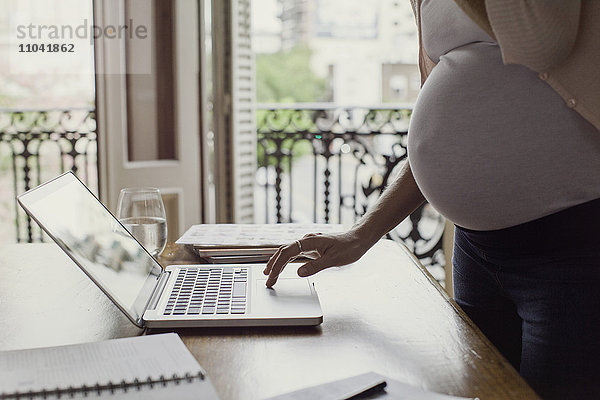 Schwangere Frau mit Laptop-Computer