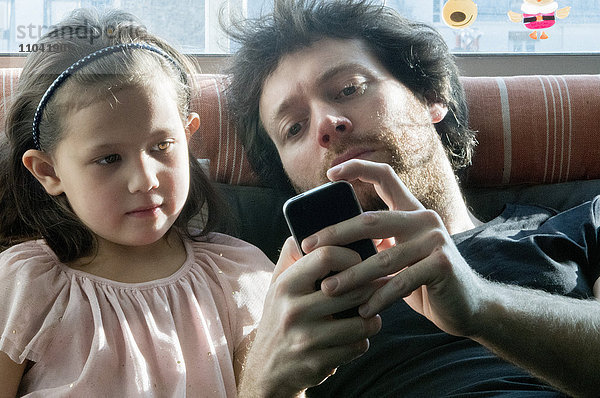 Vater und junge Tochter schauen gemeinsam auf das Smartphone