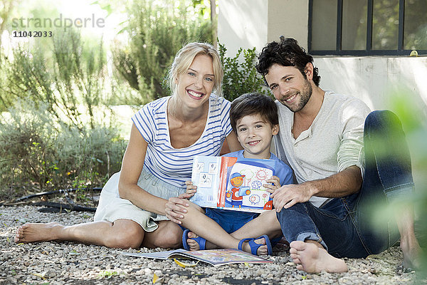 Eltern zusammen mit dem Kind lesen lernen  Portrait