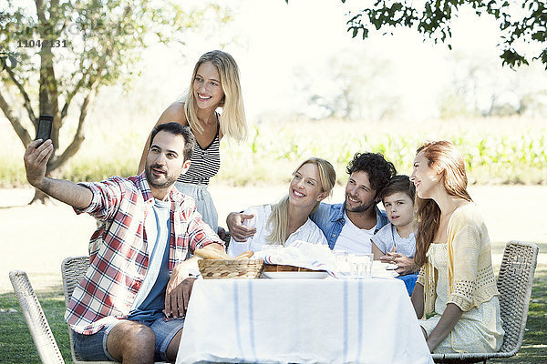 Familienposen für ein Gruppenfoto beim Picknick im Freien
