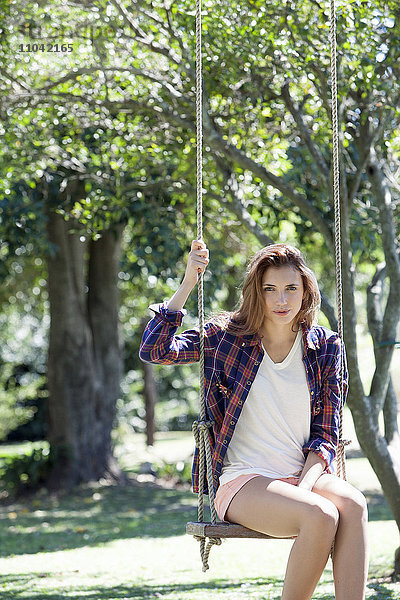 Junge Frau auf Schaukel im Park sitzend  Portrait