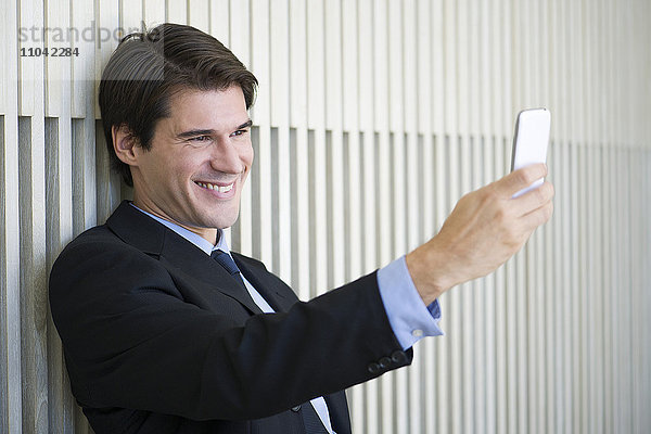 Geschäftsmann  der ein Smartphone benutzt  um einen Selfie zu nehmen.