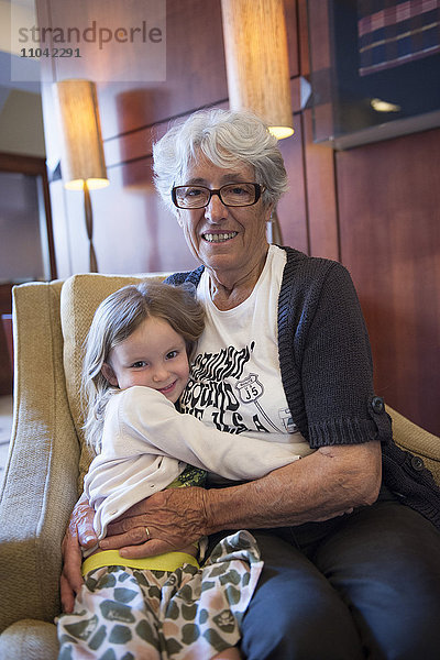 Großmutter und Enkelin umarmend im Stuhl  Portrait