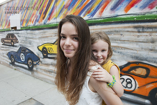 Teenagermädchen beim Huckepackfahren ihrer kleinen Schwester  Portrait