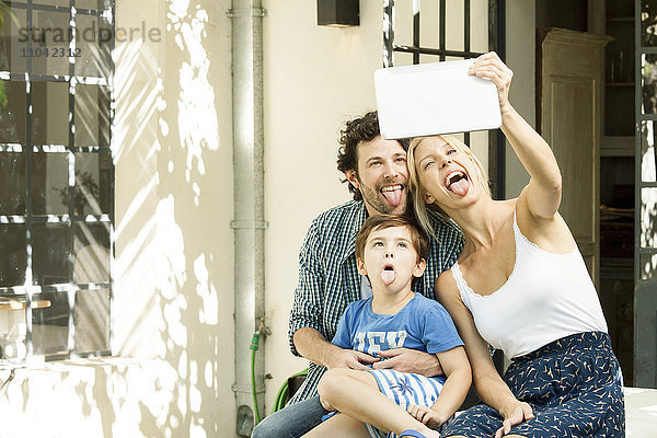 Familie mit einem Kind  das für Selfie posiert und mit einem digitalen Tablett aufgenommen wurde.