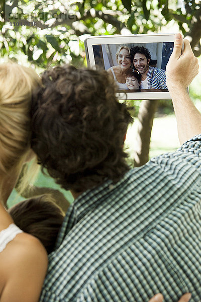 Familie mit einem Kind  das für Selfie posiert und mit einem digitalen Tablett aufgenommen wurde.