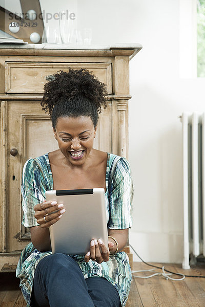 Frau lacht  während sie ein digitales Tablett benutzt.
