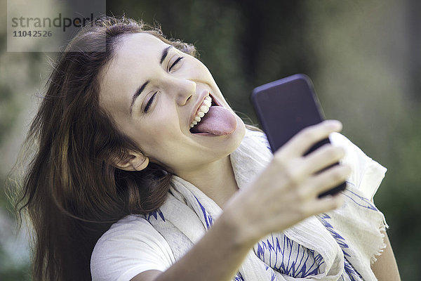 Frau nimmt Selfie mit herausstehender Zunge