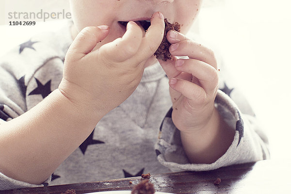 Kind isst Kuchen mit den Händen