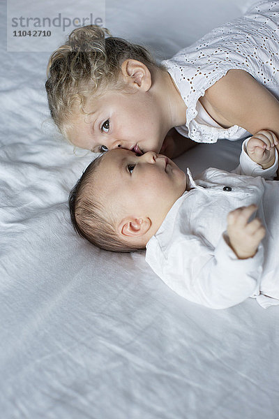 Kleines Mädchen kuschelt mit dem kleinen Bruder