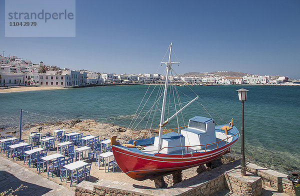 Boot und Restauranttische auf der Terrasse am Meer