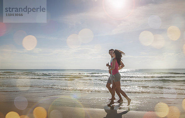 Kaukasisches Paar joggt am Strand