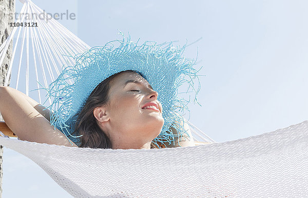 Kaukasische Frau mit Sonnenhut in der Hängematte