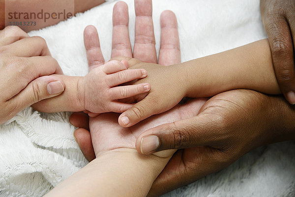 Verflochtene Hände einer gemischtrassigen Familie