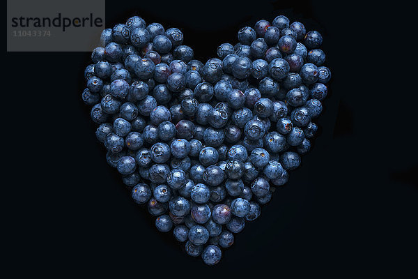 Blaubeeren in Form eines Herzens auf schwarzem Hintergrund