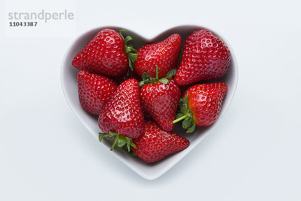 Erdbeeren in herzförmiger Schale auf weißem Hintergrund