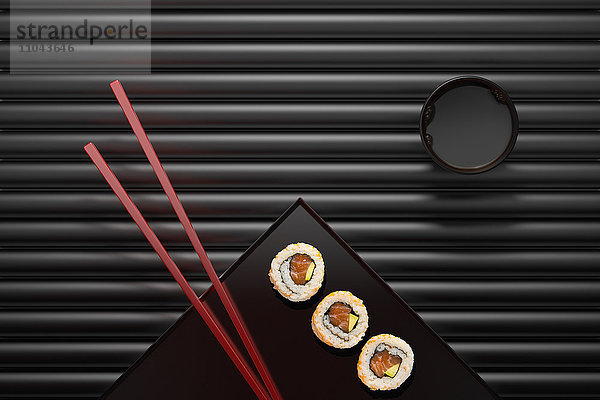 Stäbchen und Sushi auf quadratischem Teller mit Dip-Sauce