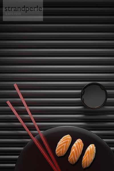 Stäbchen und Sushi auf rundem Teller mit Dip-Sauce