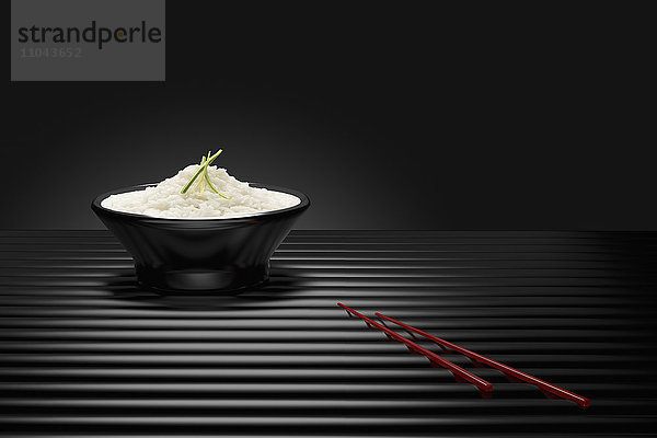 Stäbchen neben einer Schüssel mit weißem Reis