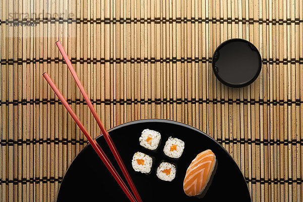 Stäbchen und Sushi auf rundem Teller mit Dip-Sauce