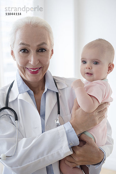 Kaukasischer Kinderarzt hält Baby-Patient