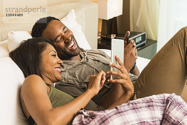 Ehepaar benutzt digitales Tablet auf dem Bett