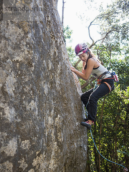 Gemischtrassiges Mädchen klettert auf Felsen