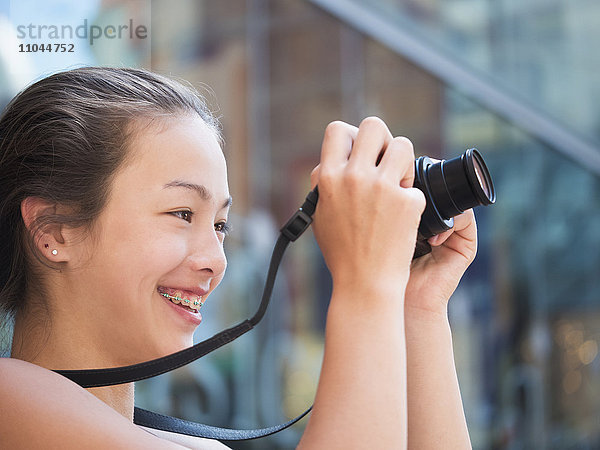 Gemischtrassiges Mädchen beim Fotografieren im Freien mit Digitalkamera