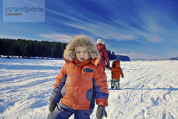 Mutter und Söhne gehen in einem verschneiten  abgelegenen Feld spazieren