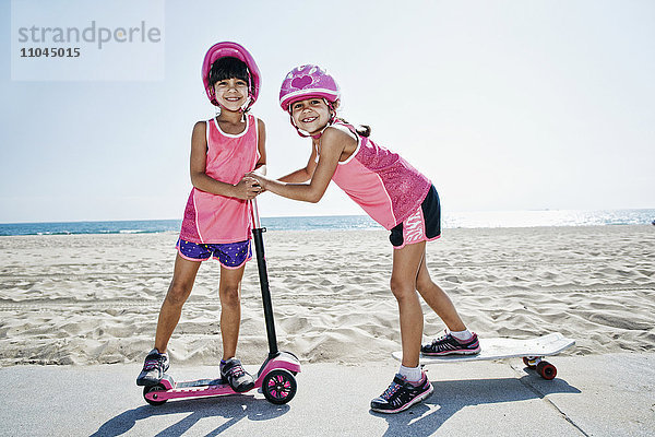 Mädchen spielen auf Skateboard am Roller am Strand