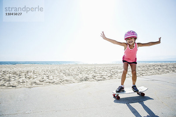 Mädchen fährt Skateboard am Strand