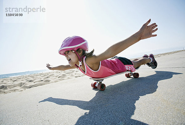 Mädchen fährt Skateboard am Strand