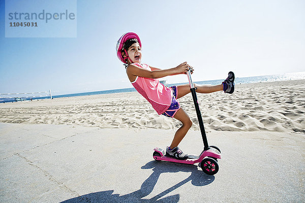Mädchen fährt Motorroller am Strand