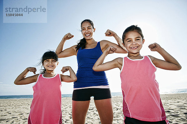 Mutter und Töchter beim Muskelspiel am Strand