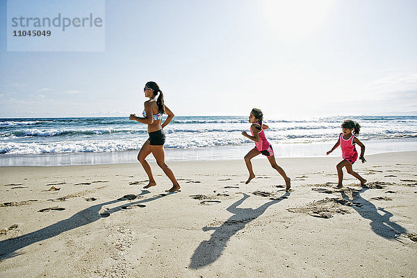 Mutter und Töchter laufen am Strand