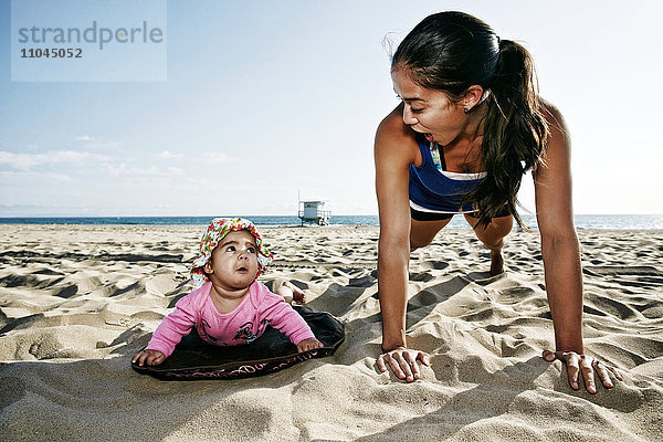 Mutter und Tochter machen Liegestütze am Strand
