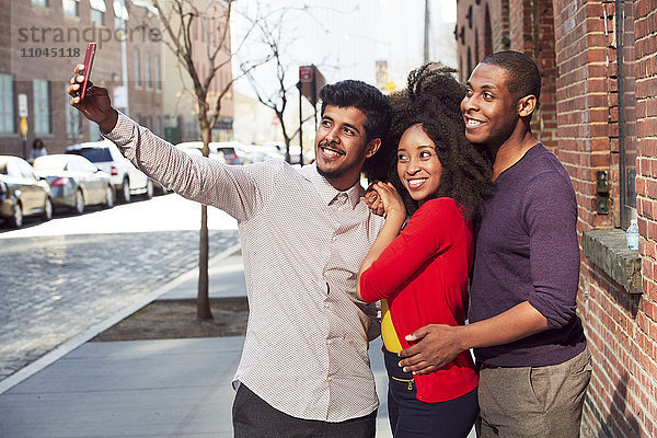 Lächelnde Freunde machen ein Selfie auf dem Bürgersteig der Stadt