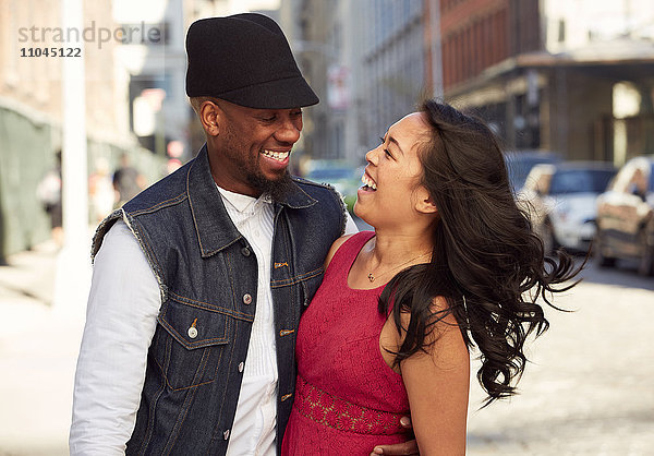Lachendes Paar auf dem Bürgersteig der Stadt