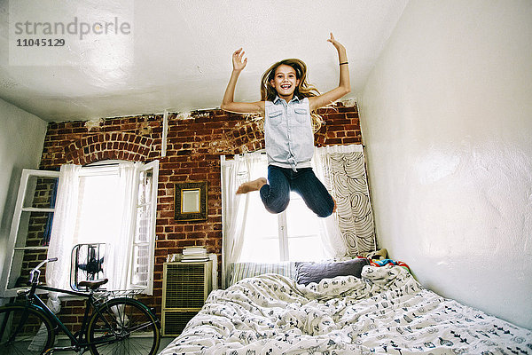 Amerikanisches Mädchen springt auf dem Bett