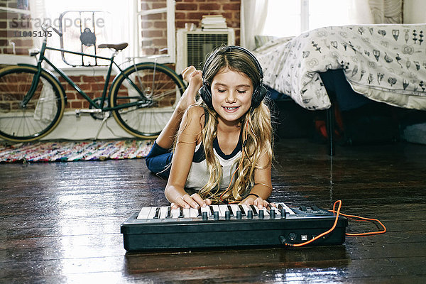 Amerikanisches Mädchen spielt Keyboard im Schlafzimmer