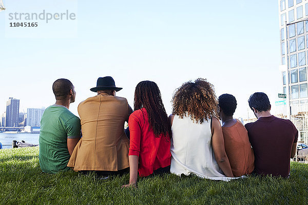 Freunde sitzen im Gras am Wasser